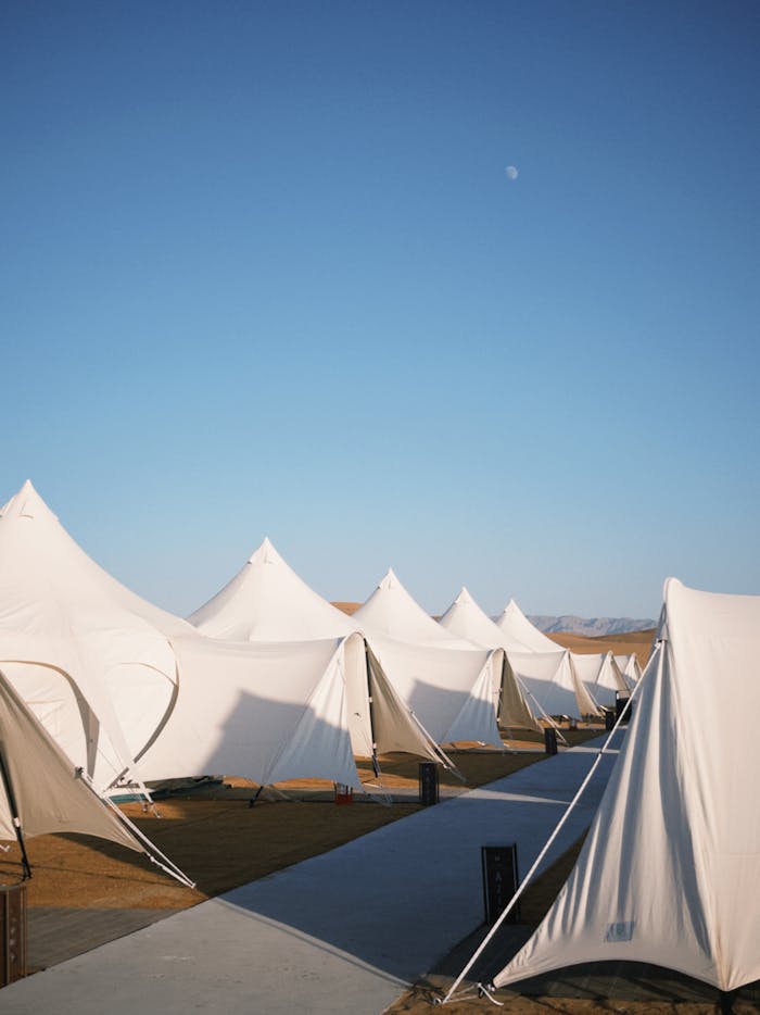 Mastering the First Impression: Your intriguing post title goes here Elegant glamping tents set against a clear blue sky in a serene desert environment.