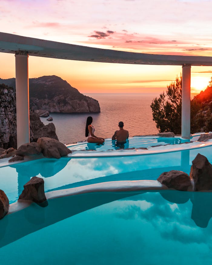 The Art of Drawing Readers In: Your attractive post title goes here Couple enjoying a serene sunset view over Ibiza's stunning coastline from a luxury resort pool.